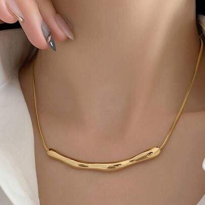 Gold necklace worn by a person with a neutral background