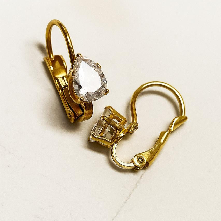 Gold earrings with clear gemstones on a light background