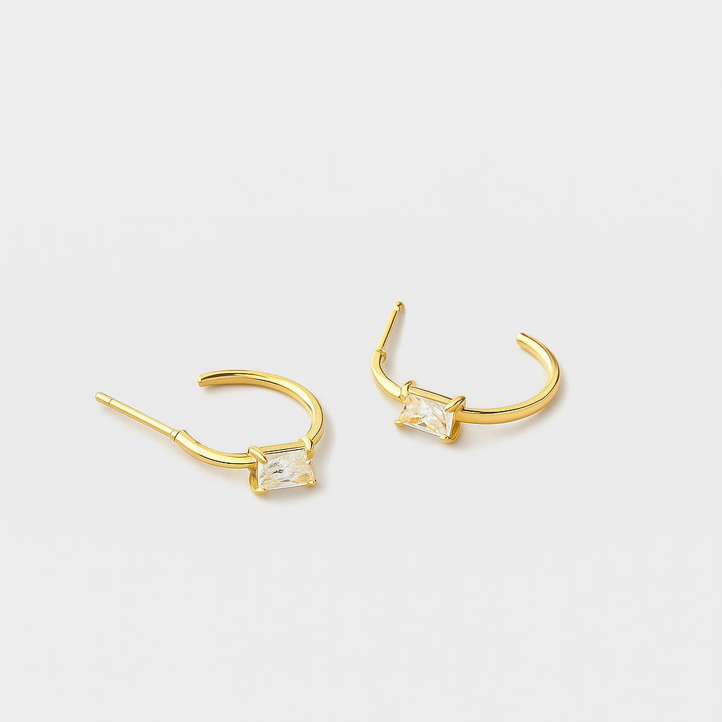 Gold hoop earrings with clear gemstones on a light gray background