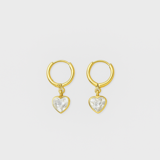 Gold heart-shaped earrings with clear stones on a light gray background