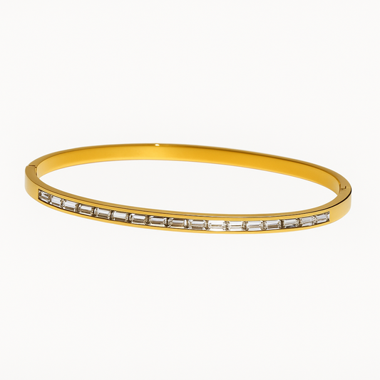 Gold bangle with embedded stones on a white background