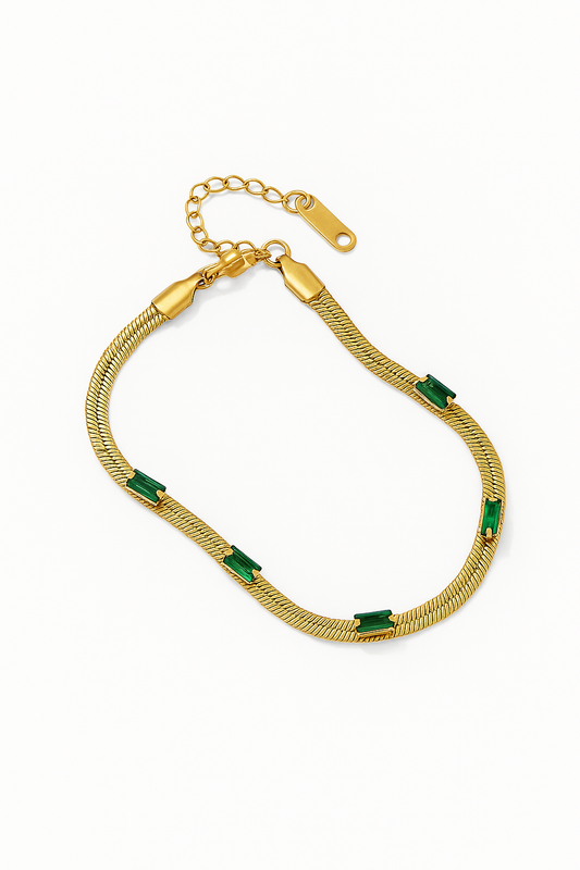 Gold bracelet with green stones on a white background