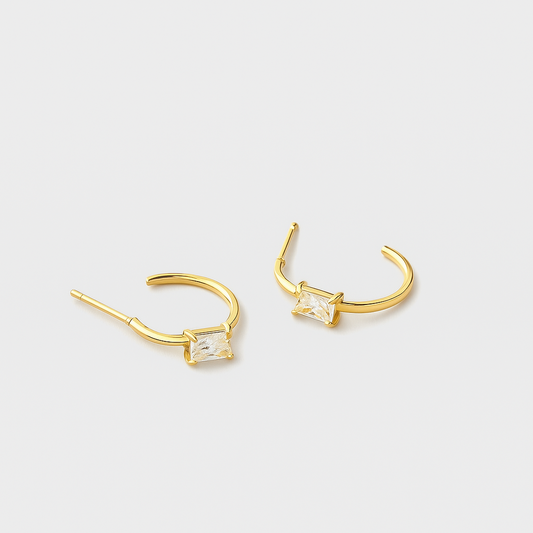 Gold hoop earrings with clear gemstones on a light gray background